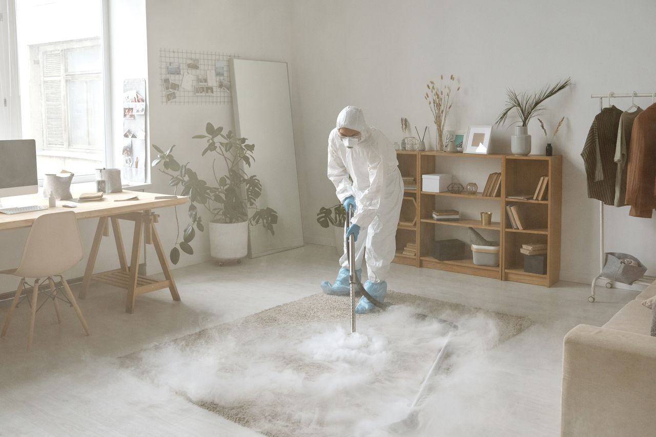 team-01 A person in protective gear disinfects a room with smoke, helping keep it safe from germs.